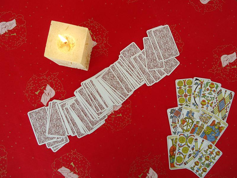 Tarotové karty na červeném ubruse se svíčkou - devět vyložených karet